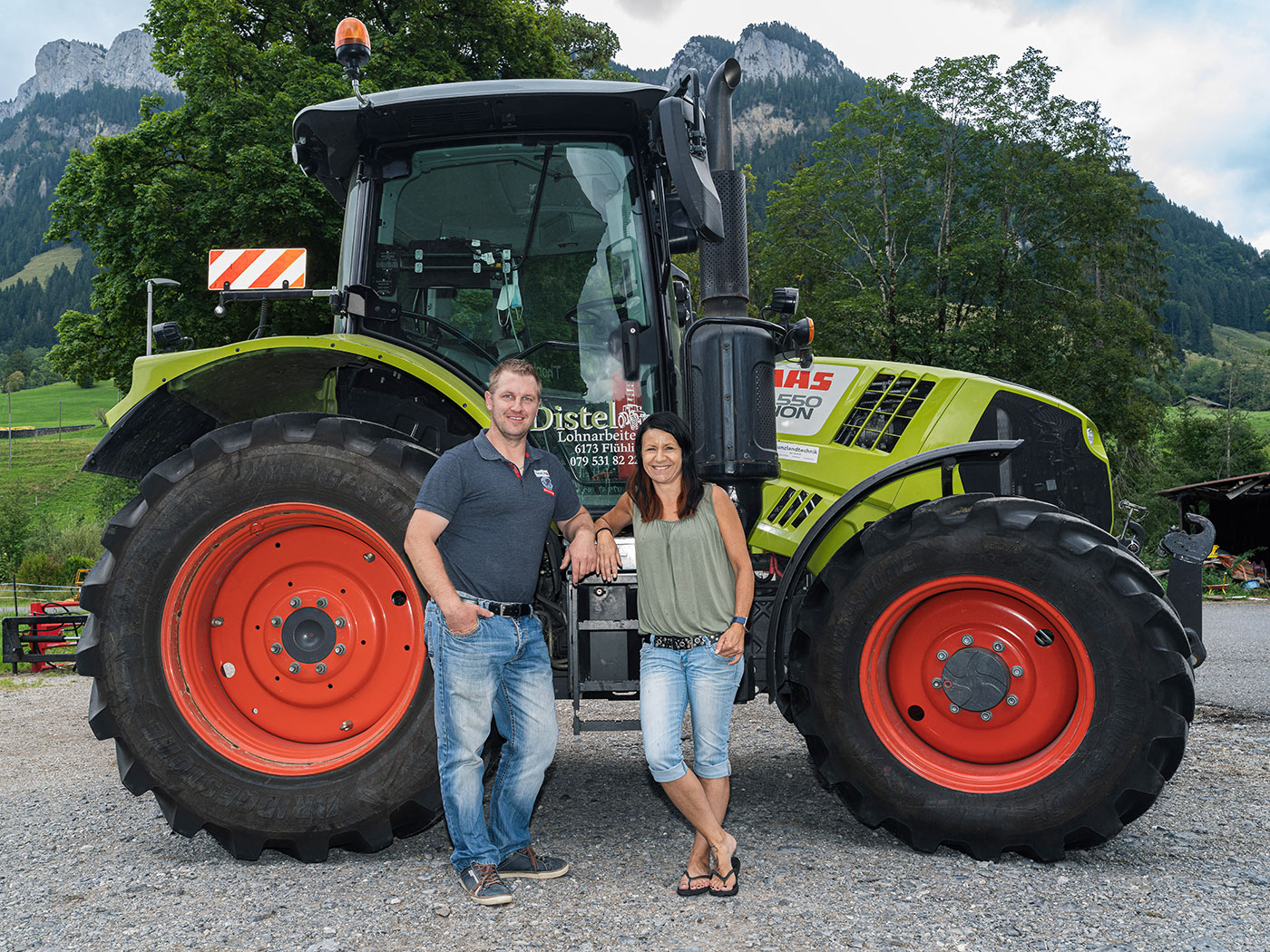Sämi und Janine Distel-Ruf vor dem Claas Arion 550 in Flühli, Distel Lohnarbeiten